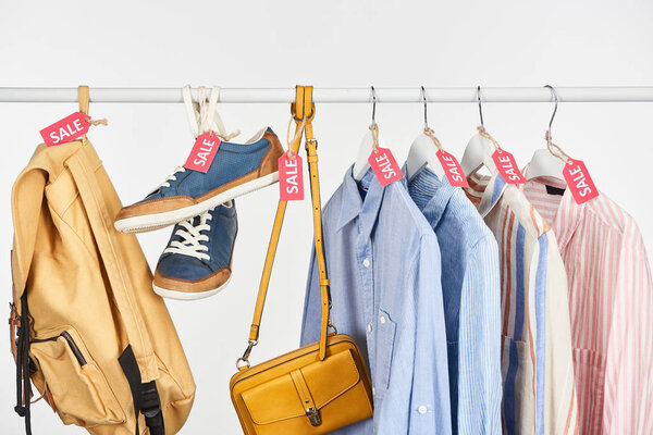 sneakers, accessories and elegant shirts hanging with sale labels isolated on white