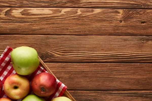 コピースペース付きの木製の表面にリンゴとチェッカーテーブルクロスのトップビュー — ストック写真