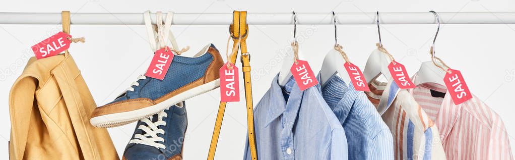 sneakers, accessories and elegant shirts hanging with sale labels isolated on white, panoramic shot