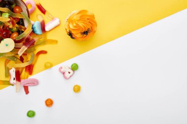 beyaz ve sarı arka plan üzerinde cupcake yakın renkli sakızlı solucanlar üst görünümü, Halloween tedavi