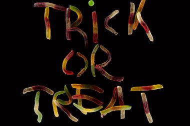 top view of colorful trick or treat lettering made of gummy worms isolated on black, Halloween treat clipart