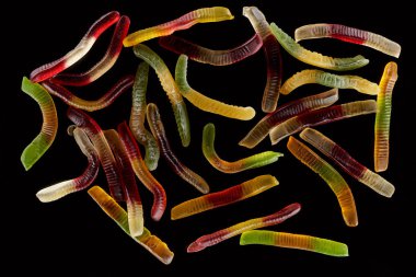 top view of colorful gummy worms isolated on black, Halloween treat clipart
