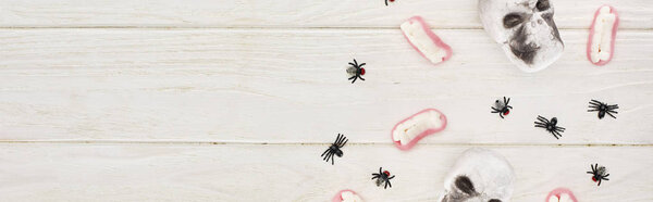 top view of gummy teeth, skulls and spiders on white wooden table, Halloween treat