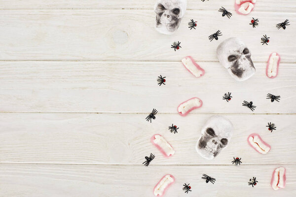 top view of gummy teeth, skulls and spiders on white table, Halloween treat