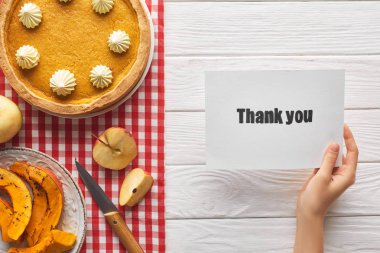 elma ile ahşap beyaz masada tatlı kabak pasta yakınında teşekkür kartı tutan kadın kırpılmış görünümü