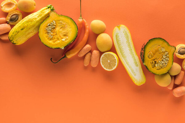top view of yellow fruits and vegetables on orange background with copy space
