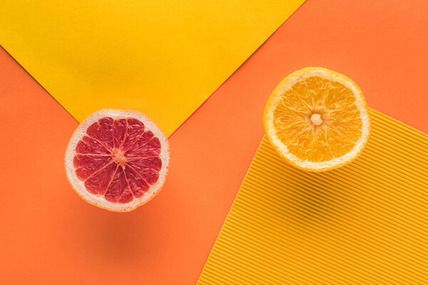 top view of orange and grapefruit on yellow and orange background with copy space