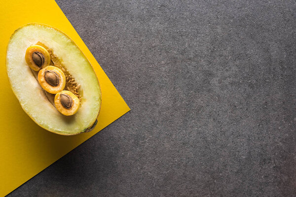 top view of melon and apricots on yellow and grey background with copy space