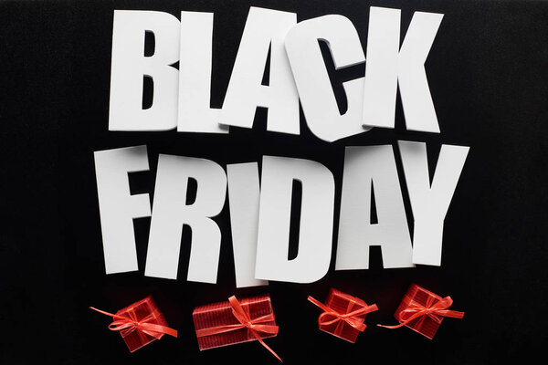 top view of black Friday lettering and red presents isolated on black