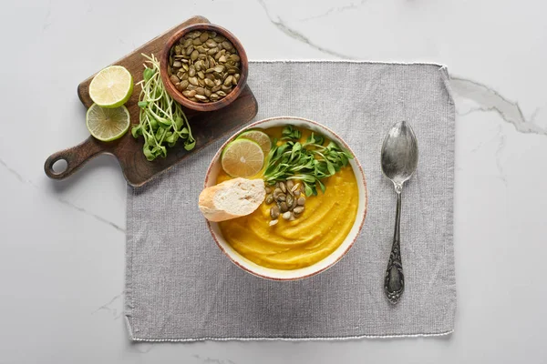 Top view of autumnal mashed pumpkin soup ion napkin with spoon near ingredients on marble surface — Stock Image Top View Autumnal Mashed Pumpkin Soup Ion Napkin Spoon Ingredients Stock Image
