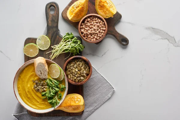 Top view of tasty mashed pumpkin soup on wooden cutting board with ingredients on marble surface — Stock Image Top View Tasty Mashed Pumpkin Soup Wooden Cutting Board Ingredients Stock Picture