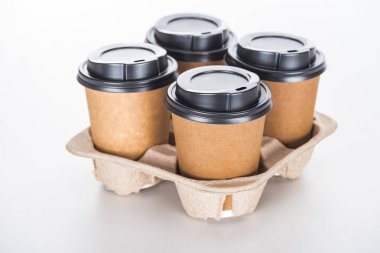 Beyaz arka planda karton tepside kahve olan kağıt bardaklar. 