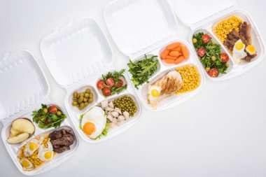 Elma, sebze, et, kızarmış yumurta ve beyaz arka planda salata içeren ekolojik paketlerin üst görünümü 