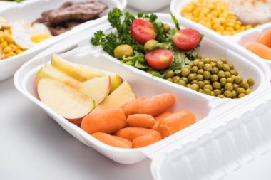 Beyaz arka planda elma, sebze ve salata içeren ekolojik paketin seçici odak noktası 