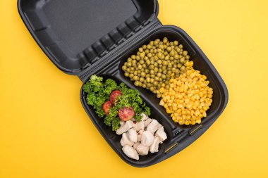 Sarı renkte sebze, et ve salata içeren ekolojik paketin üst görüntüsü 