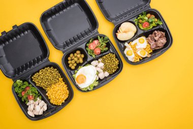 Elma, sebze, et, sahanda yumurta ve salata içeren ekolojik paketlerin üst görüntüsü sarı üzerine izole edilmiş. 