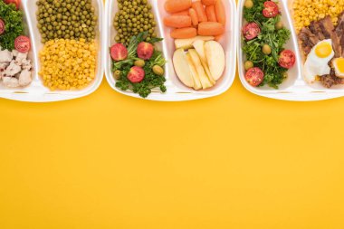 Elma, sebze, et, sahanda yumurta ve salata içeren ekolojik paketlerin üst görüntüsü sarı üzerine izole edilmiş. 