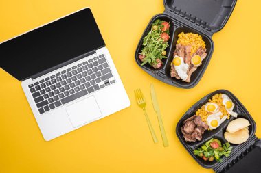 top view of laptop, eco packages with apples, vegetables, meat, fried eggs and salads isolated on yellow  clipart
