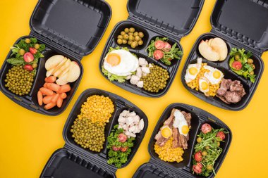 Elma, sebze, et, sahanda yumurta ve salata içeren ekolojik paketlerin üst görüntüsü sarı üzerine izole edilmiş. 