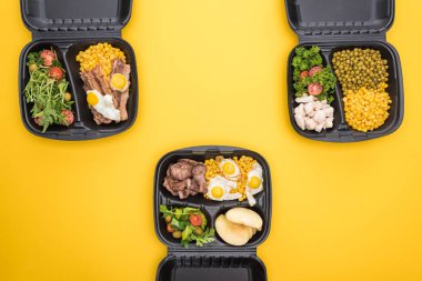 Elma, sebze, et, sahanda yumurta ve salata içeren ekolojik paketlerin üst görüntüsü sarı üzerine izole edilmiş. 