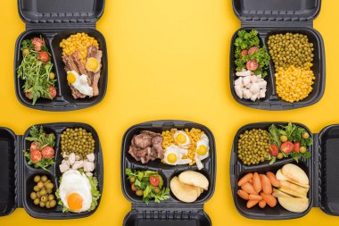 Elma, sebze, et, sahanda yumurta ve salata içeren ekolojik paketlerin üst görüntüsü sarı üzerine izole edilmiş. 
