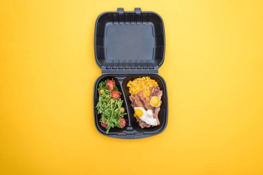 Mısır, et, sahanda yumurta ve sarılı salata içeren ekolojik paketin üst görüntüsü 