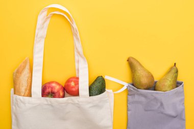 top view of ripe fruits, vegetables and baguette in eco friendly bags isolated on yellow clipart
