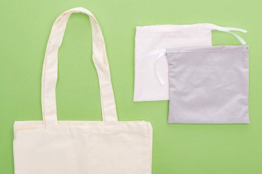 top view of empty cotton eco bags isolated on green clipart