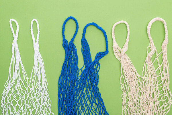 top view of empty multicolored string bags isolated on green