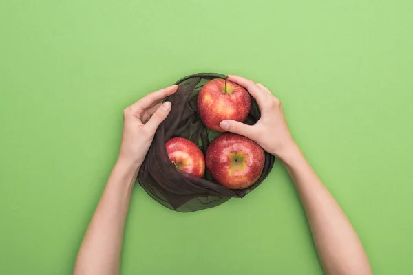 部分视图的妇女拿着红色成熟的苹果在生态友好袋隔离在绿色 — 图库照片