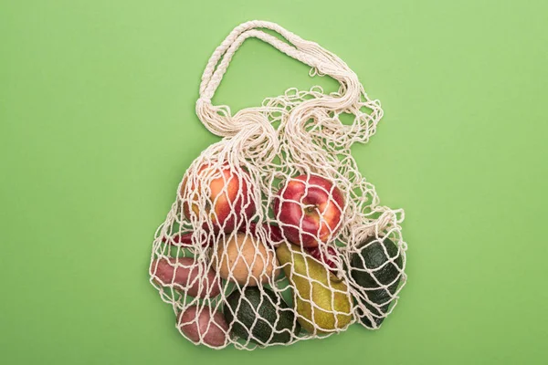 緑に隔離されたストリングバッグの野菜や果物のトップビュー — ストック写真