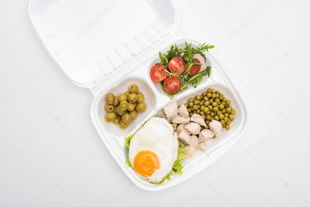 top view of eco package with vegetables, meat, fried egg and salad on white background 