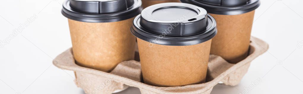 panoramic shot of paper cups with coffee in cardboard tray on white background 