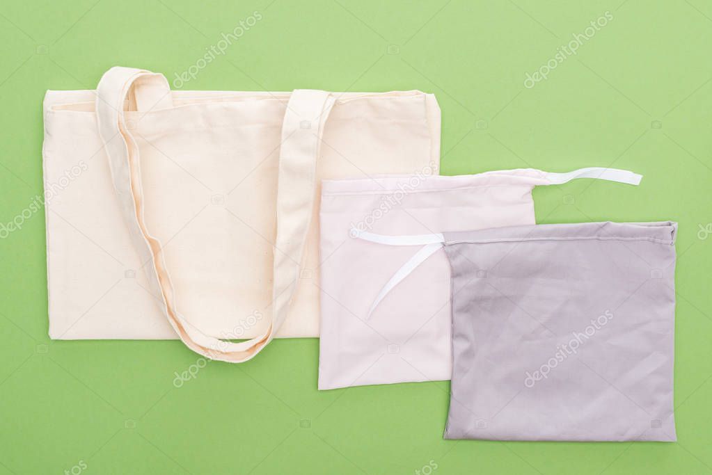 top view of empty cotton eco bags isolated on green