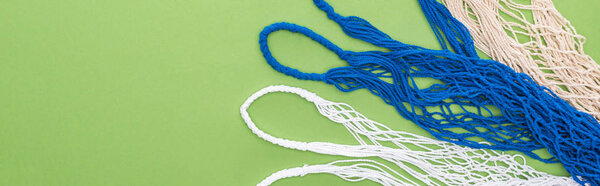 top view of empty multicolored string bags isolated on green, panoramic shot