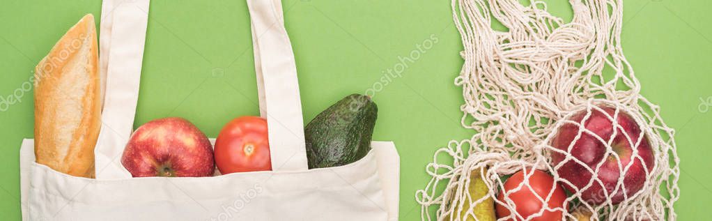 top view of fresh baguette, vegetables and fruits in cotton and string bag isolated on green, panoramic shot