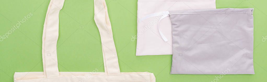 top view of empty cotton eco bags isolated on green, panoramic shot