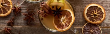 top view of traditional pear mulled wine in glass with spices on wooden rustic table, panoramic shot clipart