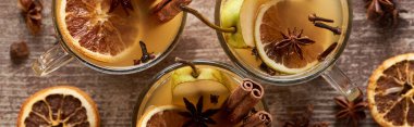 top view of traditional pear mulled wine in glasses with spices on wooden rustic table, panoramic shot clipart