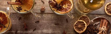 top view of traditional warm pear mulled wine with spices and dried citrus on wooden rustic table, panoramic shot clipart
