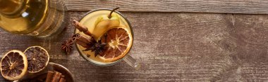 top view of warm pear mulled wine with spices and dried citrus on wooden rustic table, panoramic shot clipart