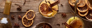 top view of warm pear mulled wine with spices and dried citrus on wooden table, panoramic shot clipart