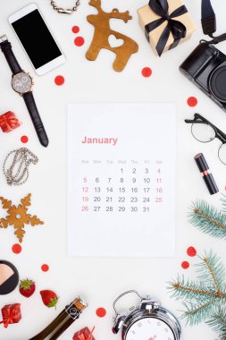 Ocak takvim sayfası, dijital kamera, çalar saat, akıllı telefon, şampanya şişesi, kozmetik, gözlük, köknar dalı, taze çilek, beyaz üzerine izole edilmiş noel mücevherleri.