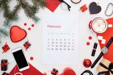 Şubat takvim sayfası, şekerli kahve, akıllı telefon, köknar dalı, kol saati, bilezikler, noel mücevherleri, kırmızı kağıt, beyaz üzerine izole edilmiş kol saati.