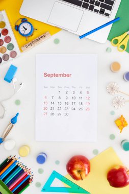 september calendar page, laptop, apples, school supplies, multicolored paper, wooden block with september inscription isolated on white  clipart