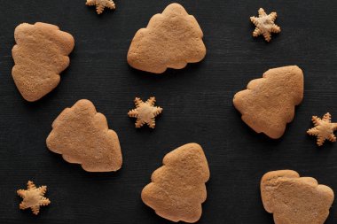 Kar taneleri ve Noel ağacı kurabiyeleri siyah ahşap masada.
