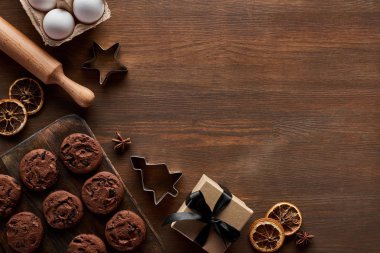 Tahta masadaki hediye kutusunun yanındaki çikolatalı Noel kurabiyelerinin üst görüntüsü.