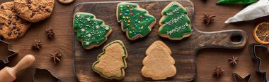 top view of glazed Christmas cookies with pastry bag on wooden cutting board, panoramic shot clipart