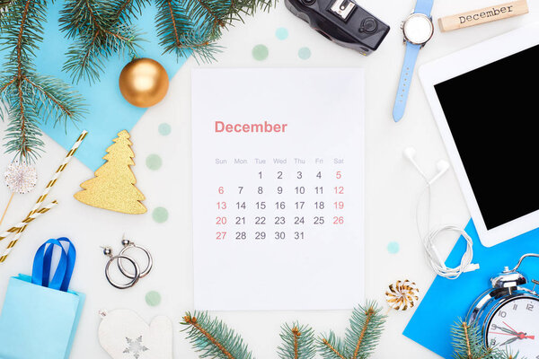 december calendar page, digital camera, chrismas baubles, fir branch, wristwatch, blue paper, wooden block with december inscription, isolated on white