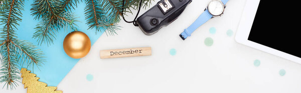 панорамный снимок цифрового планшета, ель ветви, наручные часы, рождественские безделушки, деревянный блок с декабрьской надписью изолирован на белом
